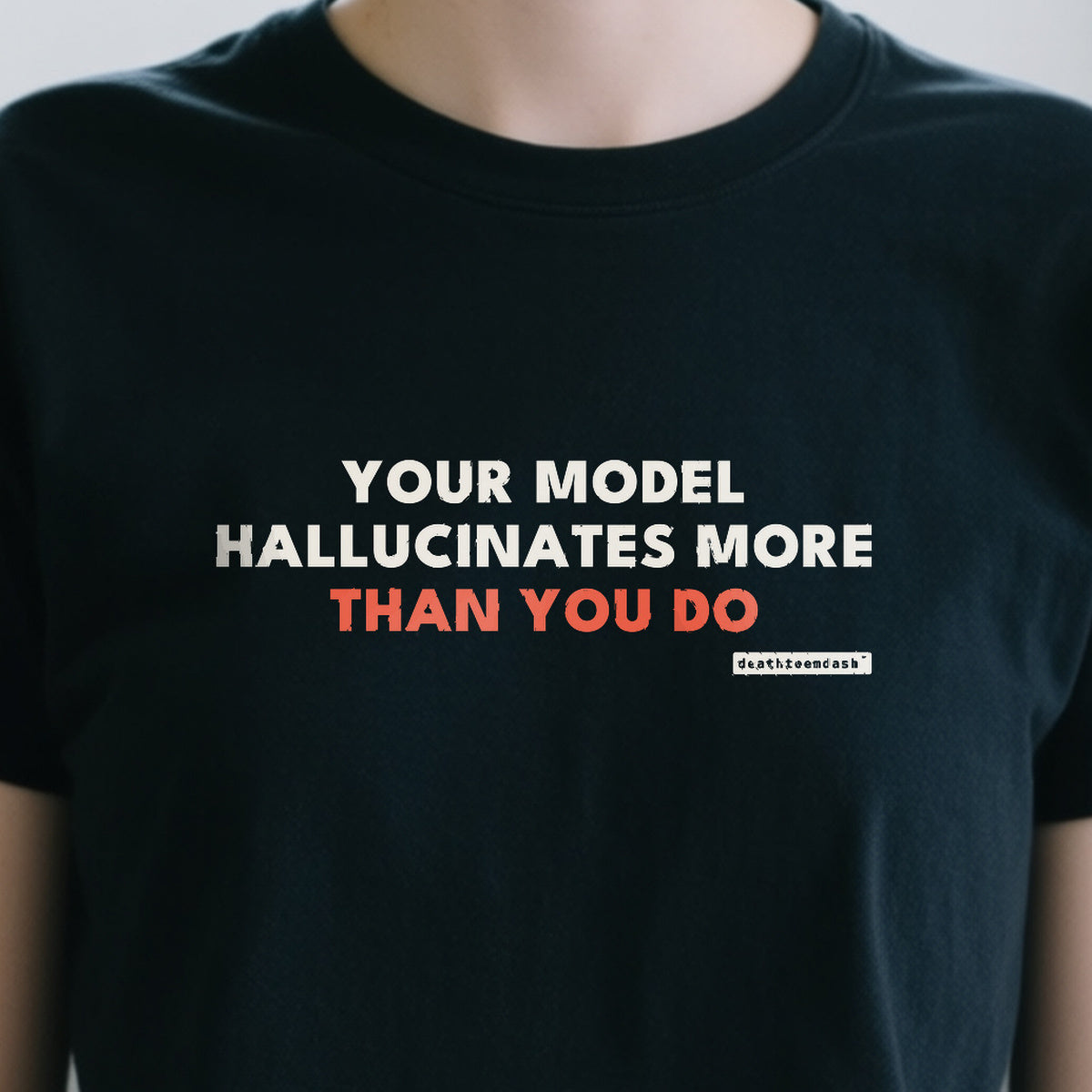 Your Model Hallucinates More Than You Do design shown close up on a black unisex t-shirt